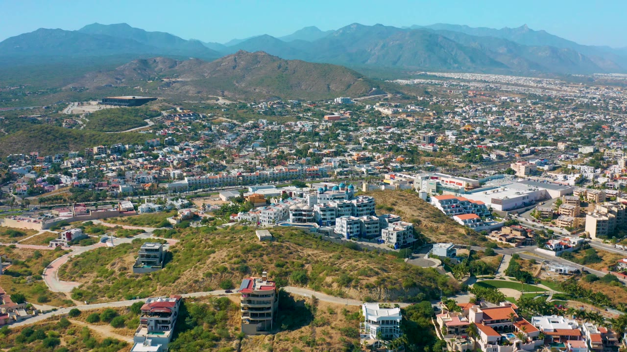 Aerial cityscape with hillside foreground and mountain skyline