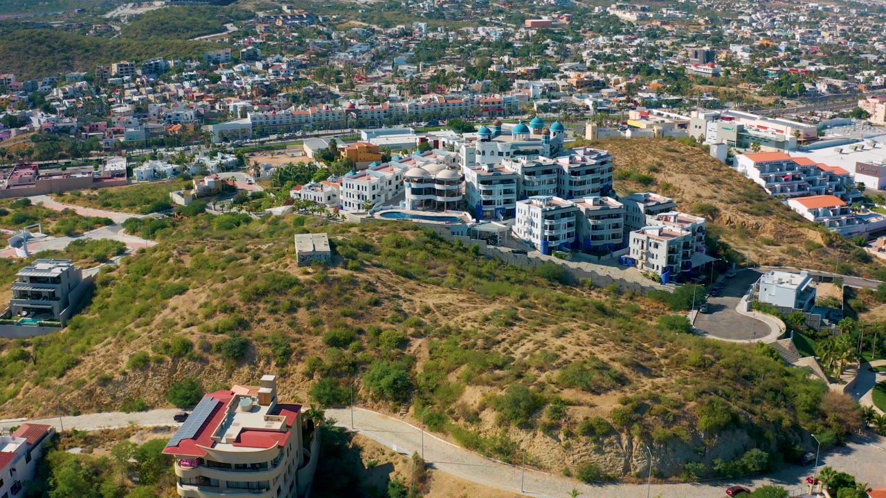 Residential buildings on a dry hillside with city blocks behind.