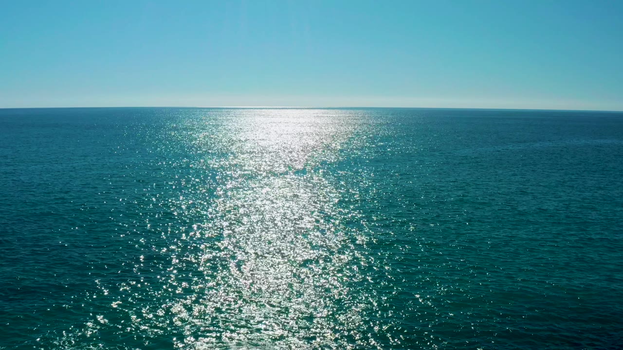 Wide ocean frame from San Jose del Cabo with the glittering sun path shifted toward the right side of the composition and no visible people.