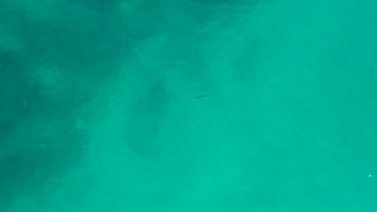 Clear green-blue shallows with the small craft slightly farther across frame.