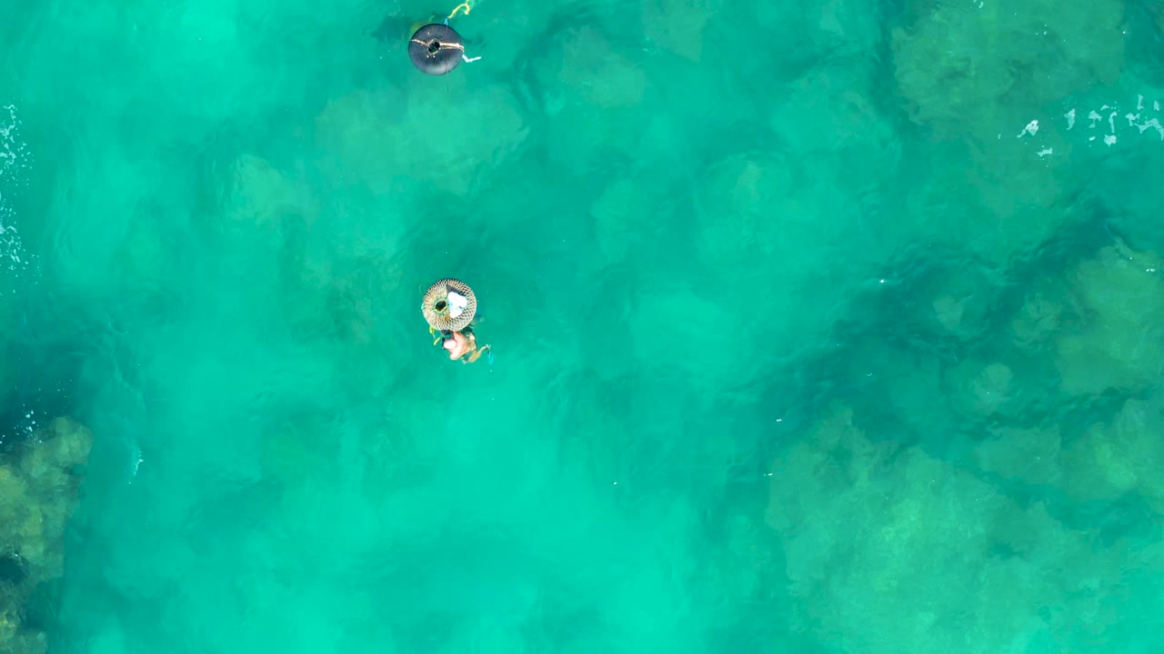 Overhead turquoise water with two inflatable ring floaters.