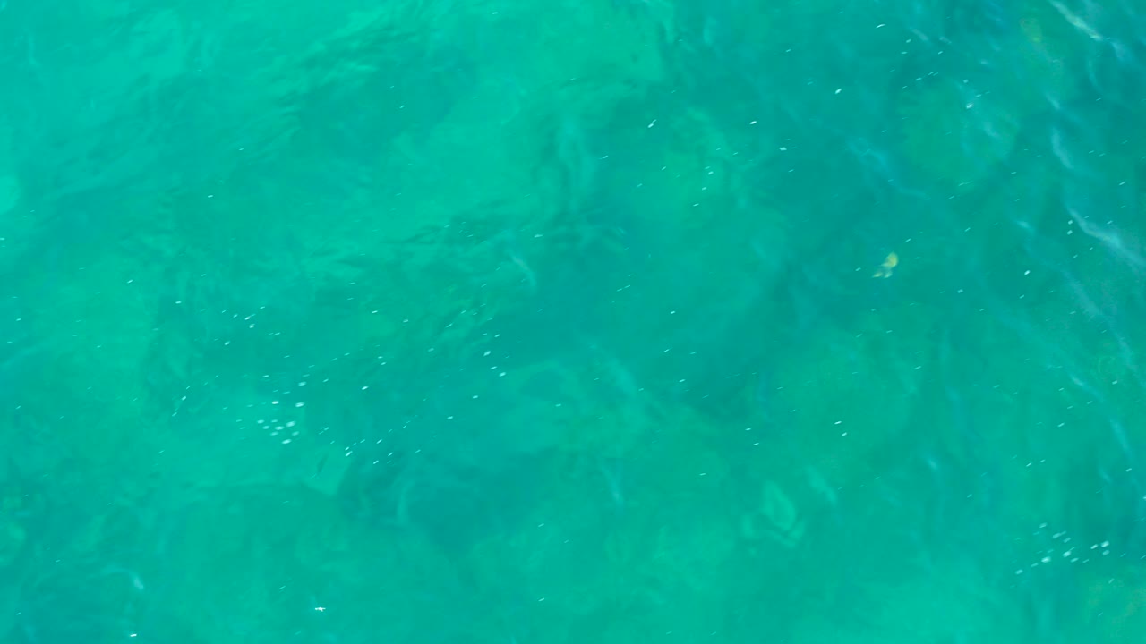 Turquoise water surface over faint submerged rocks