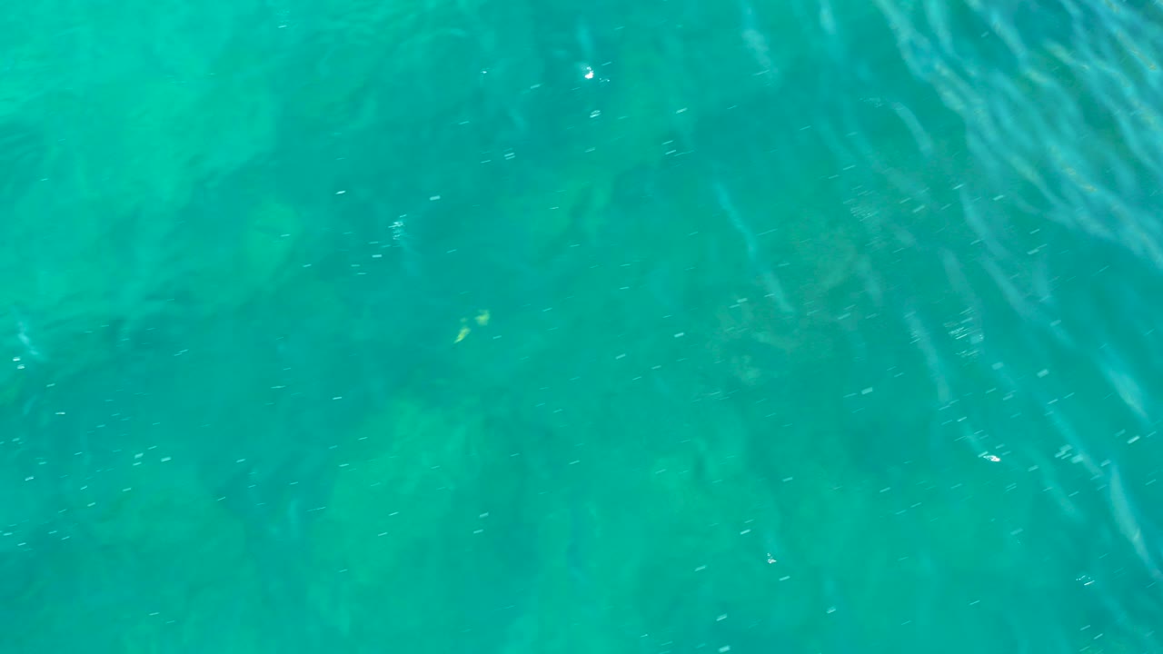Turquoise water with ripples over submerged rocks.