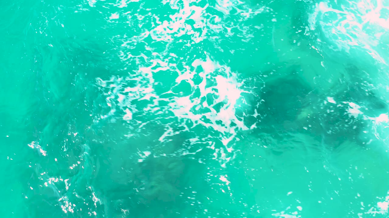 White foam patterns drifting over clear turquoise water