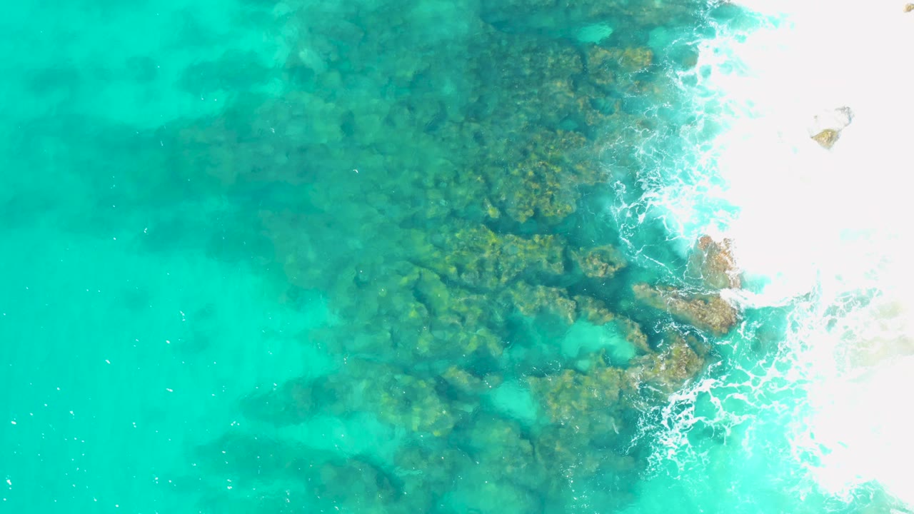 Submerged rocks and foamy waves seen from directly above.