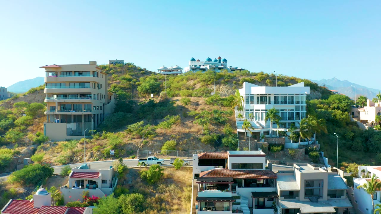 Modern hillside homes beside a road under clear sky