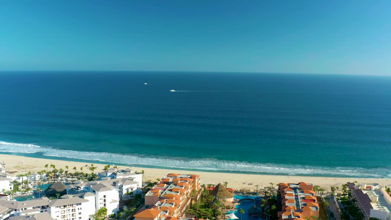 Boat offshore from a sandy beach and resort buildings