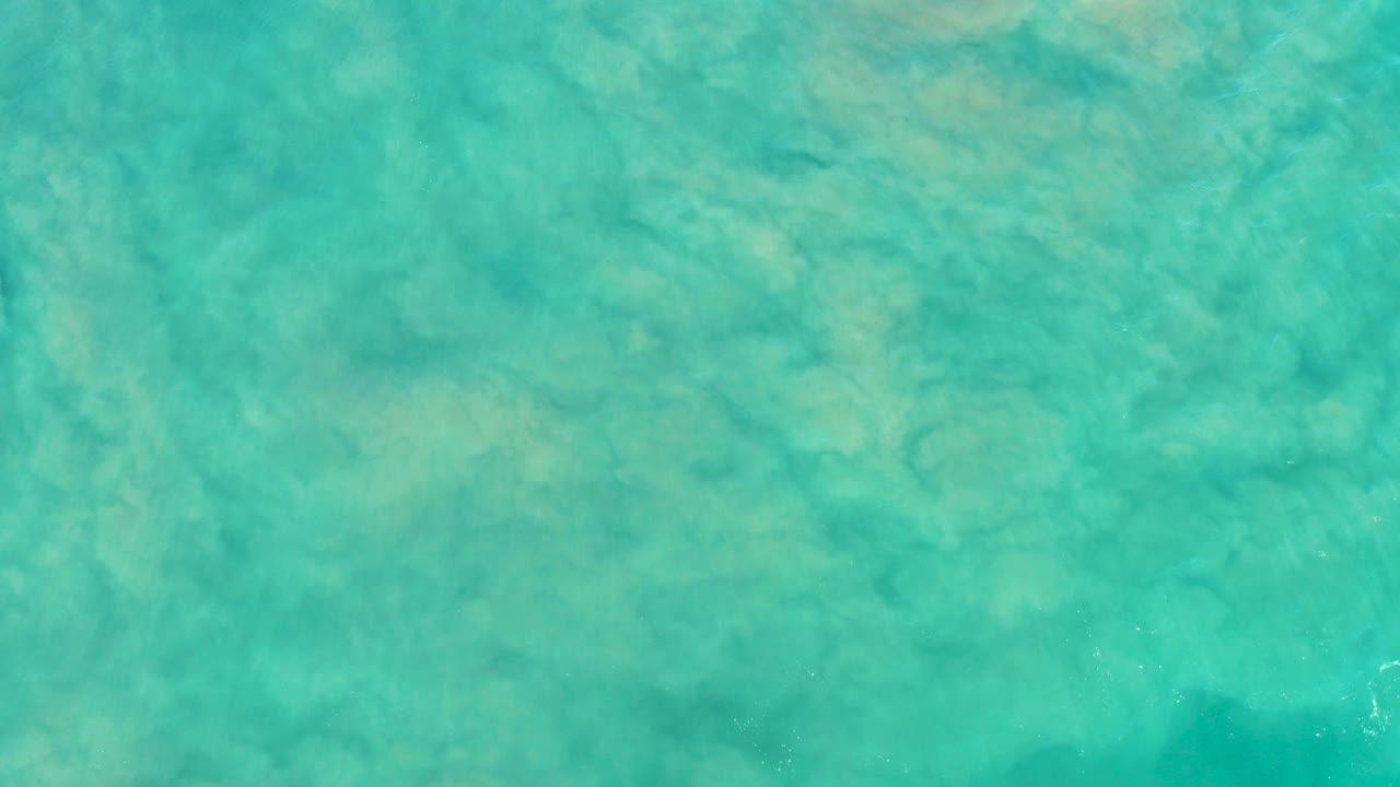 Overhead turquoise shallow ocean water with sandy bottom patterns.