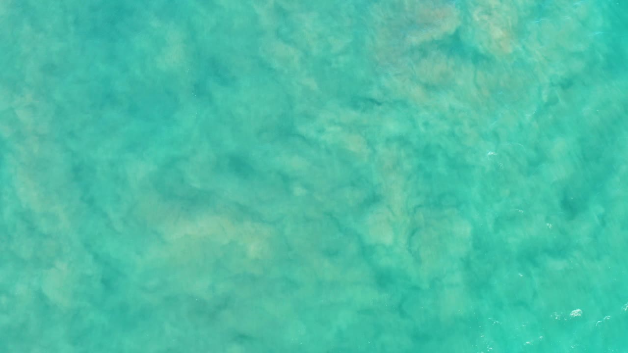 Overhead San Jose del Cabo shallow water view with green-turquoise tones, tan bottom patterns, and no visible people.