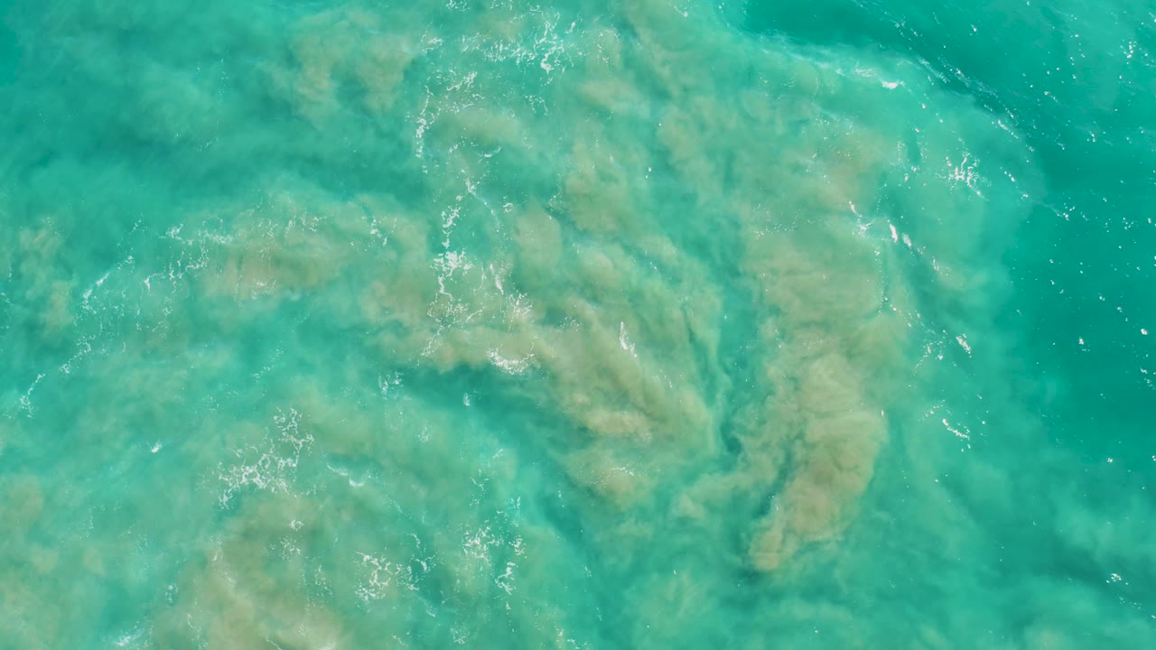 A top-down San Jose Del Cabo water frame shows coral-like underwater texture surrounded by clear blue-green water and fine surface sparkle, no visible people.