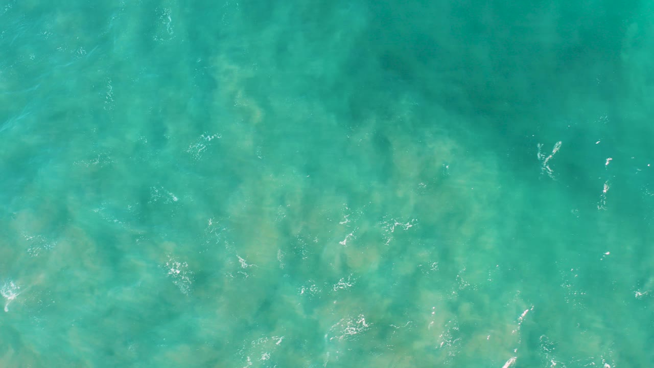 Turquoise ocean water with sandy seabed visible below.