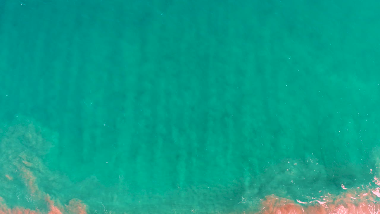 Overhead turquoise ocean water with faint underwater sand ridges