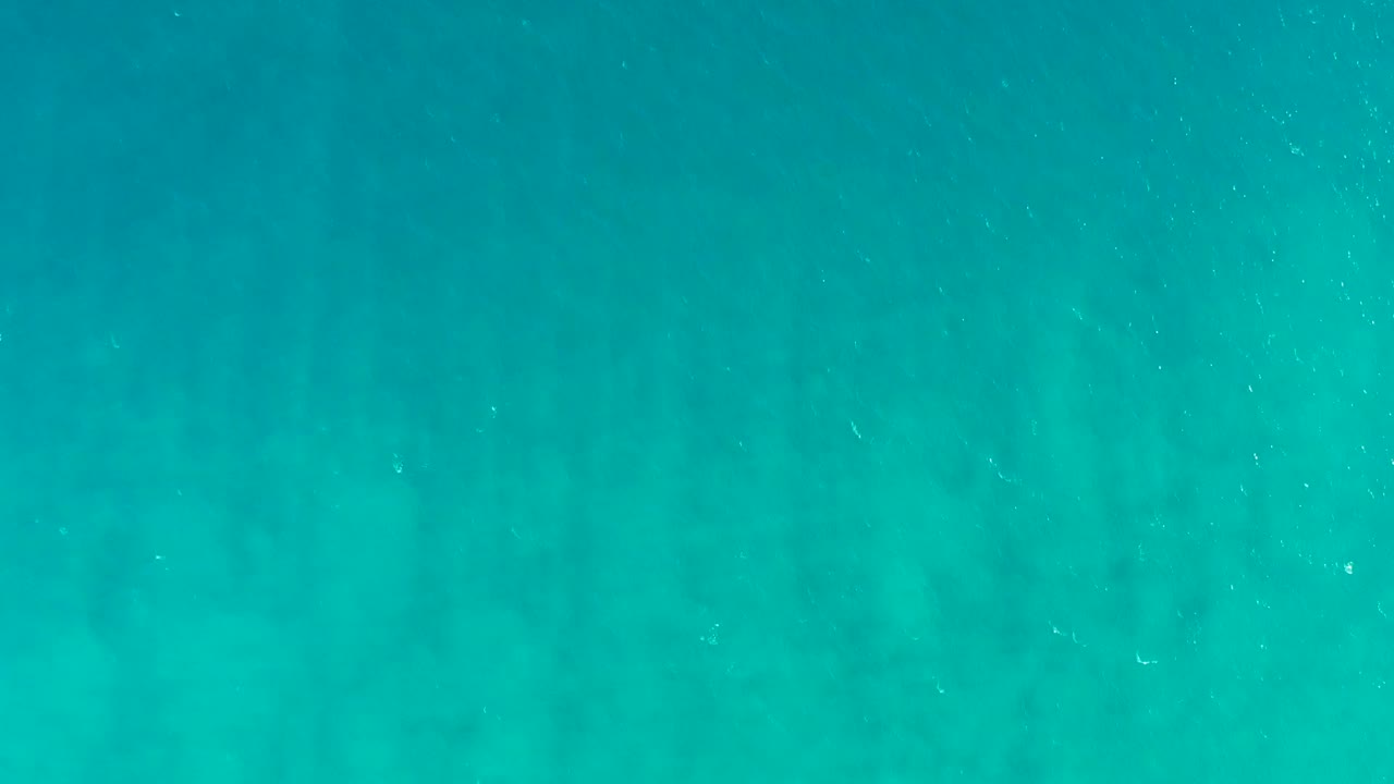 Clear blue-green underwater frame from San Jose del Cabo with soft vertical seaweed-like lines and tiny white particles, no visible people.