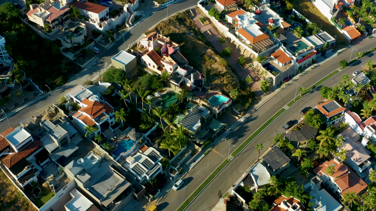 Aerial view of a residential road cutting between houses and trees.