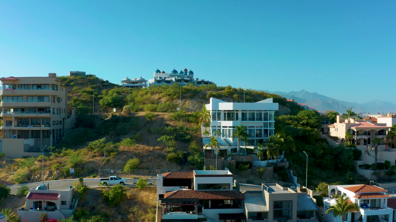 Hillside residences with foreground rooftops and clear blue sky.