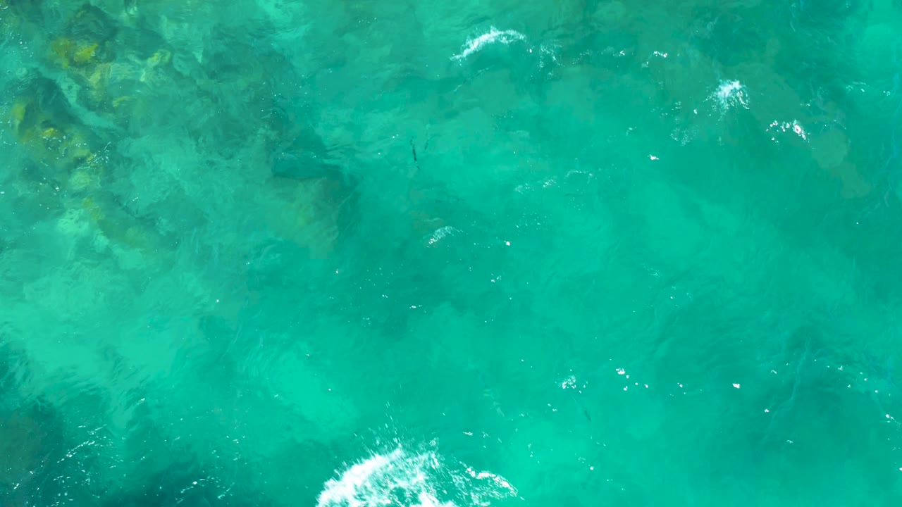 Clear water with small white foam near submerged rocks