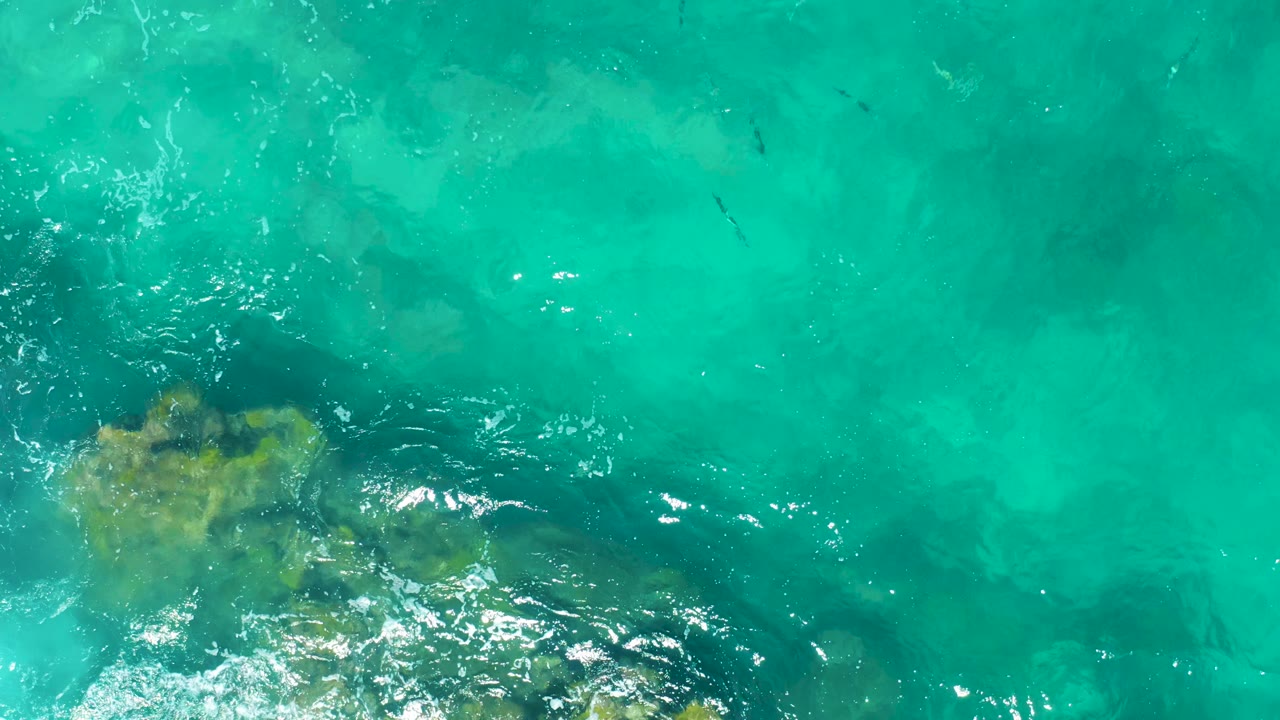 Turquoise water and rocks at the lower left.