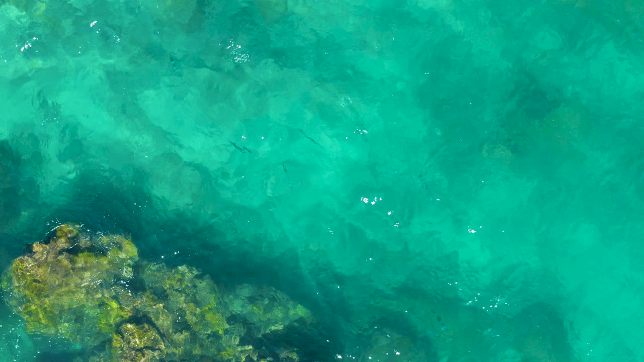 Turquoise shallow water over submerged rocks