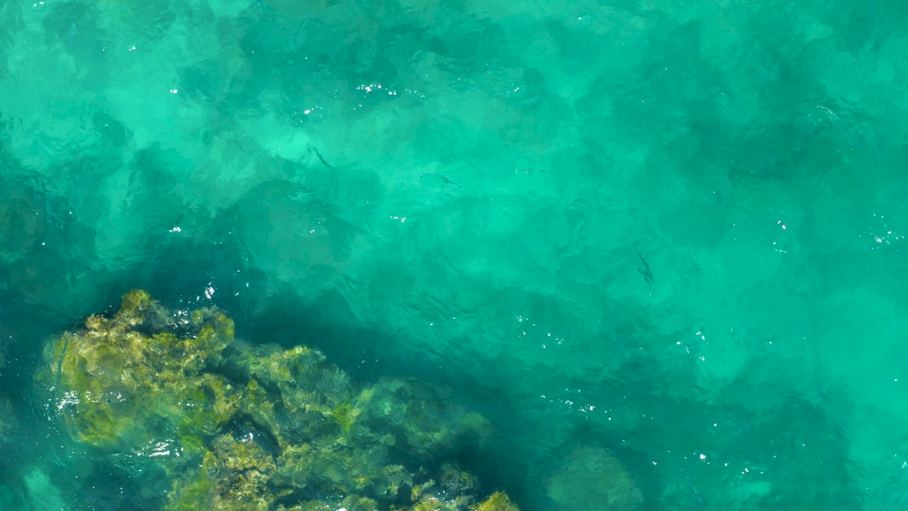 Turquoise shallow water over submerged rocks