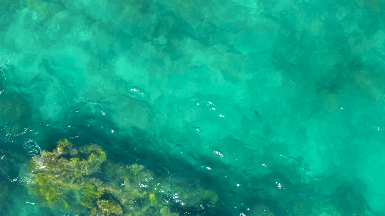 Turquoise water over submerged rocks and ripples