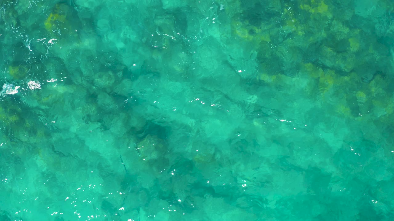 Turquoise water over mottled underwater rocks