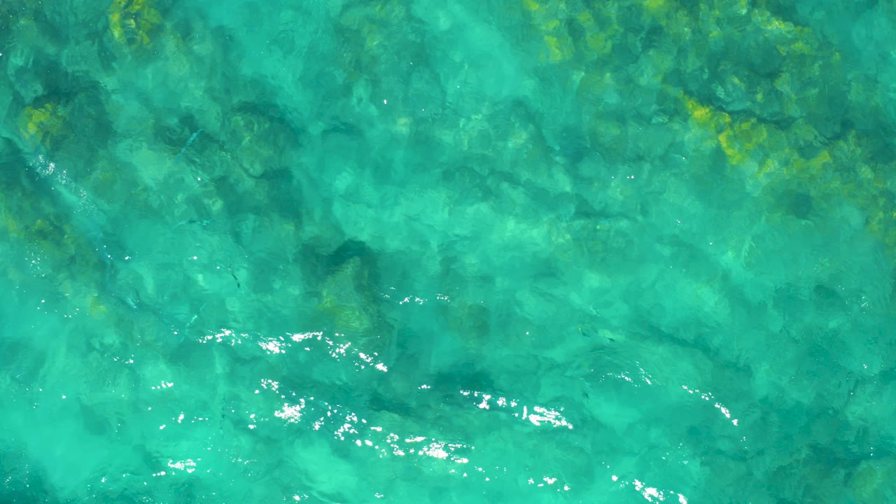 Turquoise ocean water over dark underwater rocks