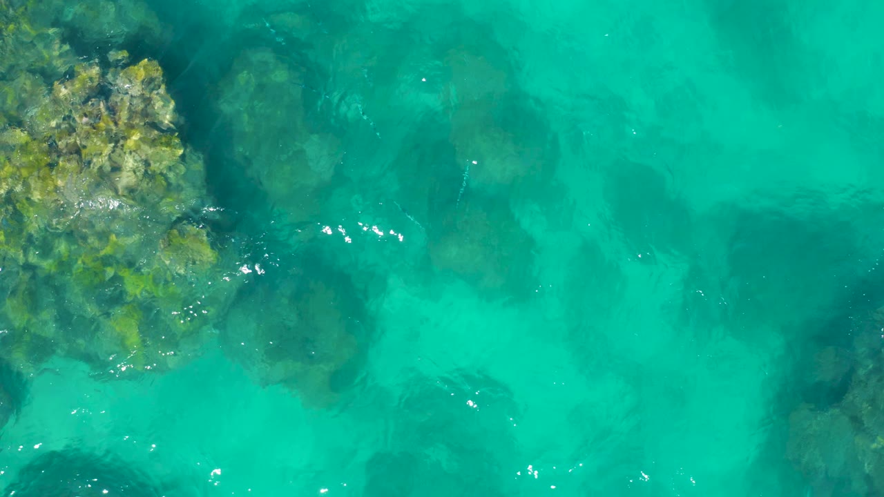 Turquoise water with rocky shoreline edge along the left side.