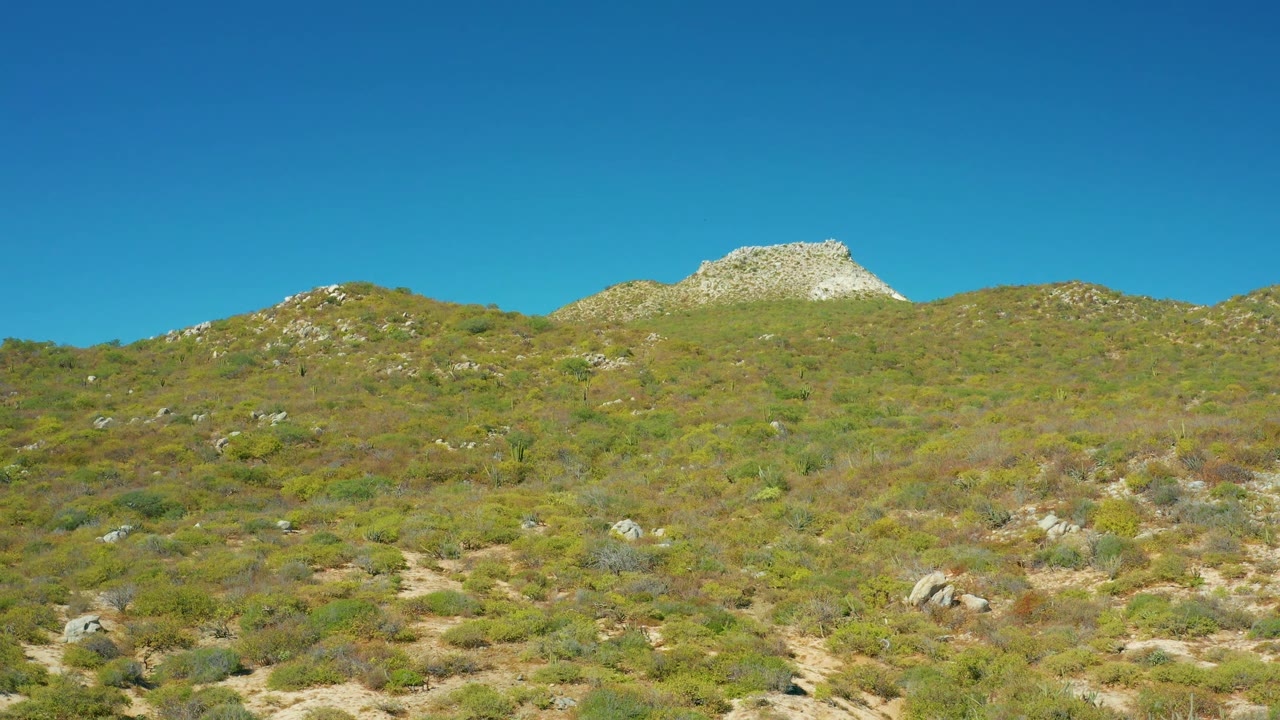 East Cape BCS Mexico frame with the rocky ridge and rounded hills spread across the horizon, dry shrubland below, and no visible people.
