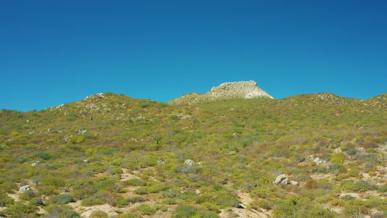 Sparse green and brown hillside vegetation with rocky ridgeline.