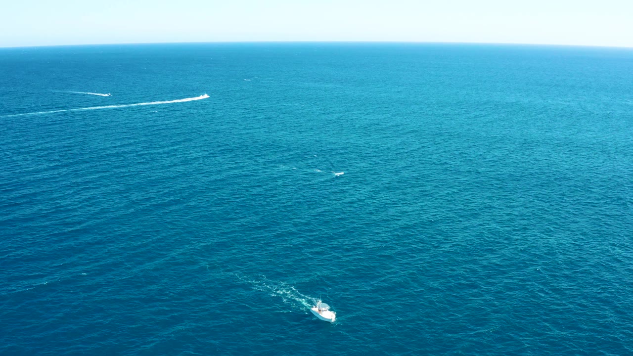 Wide aerial ocean view with boats leaving long wakes
