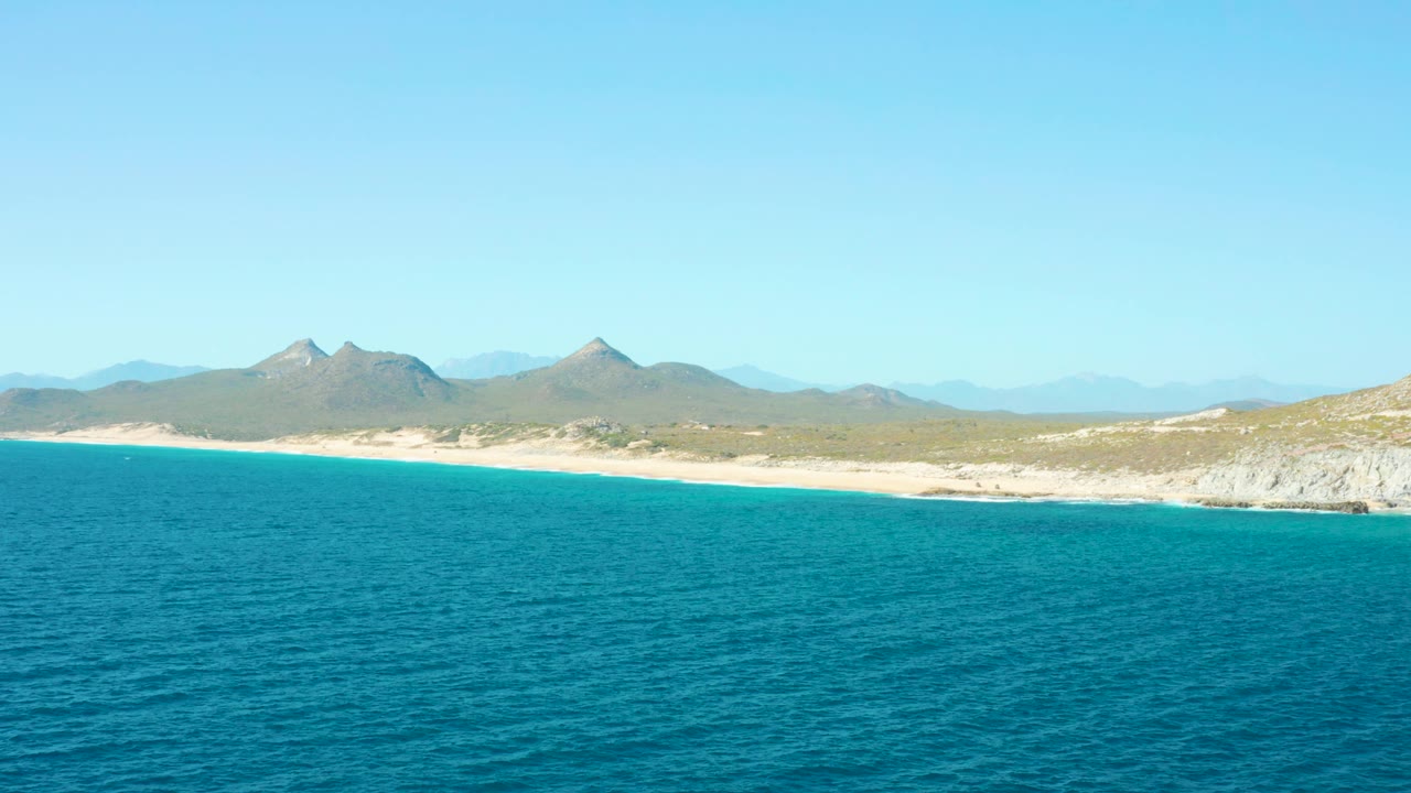 Wide coastline with rippled ocean, beach, and mountains.