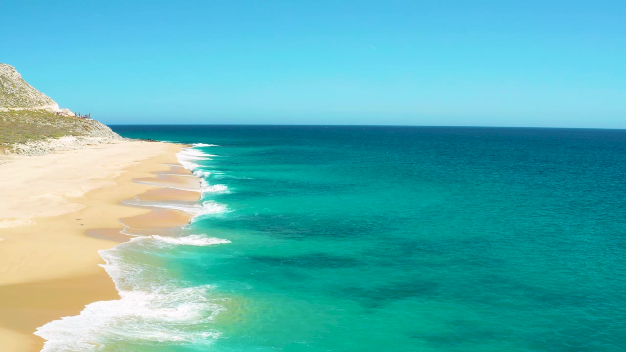 East Cape, Baja California Sur beach seen from above with the surf line slightly farther right, pale sand exposed along the left edge, open ocean to the right, and no visible people.