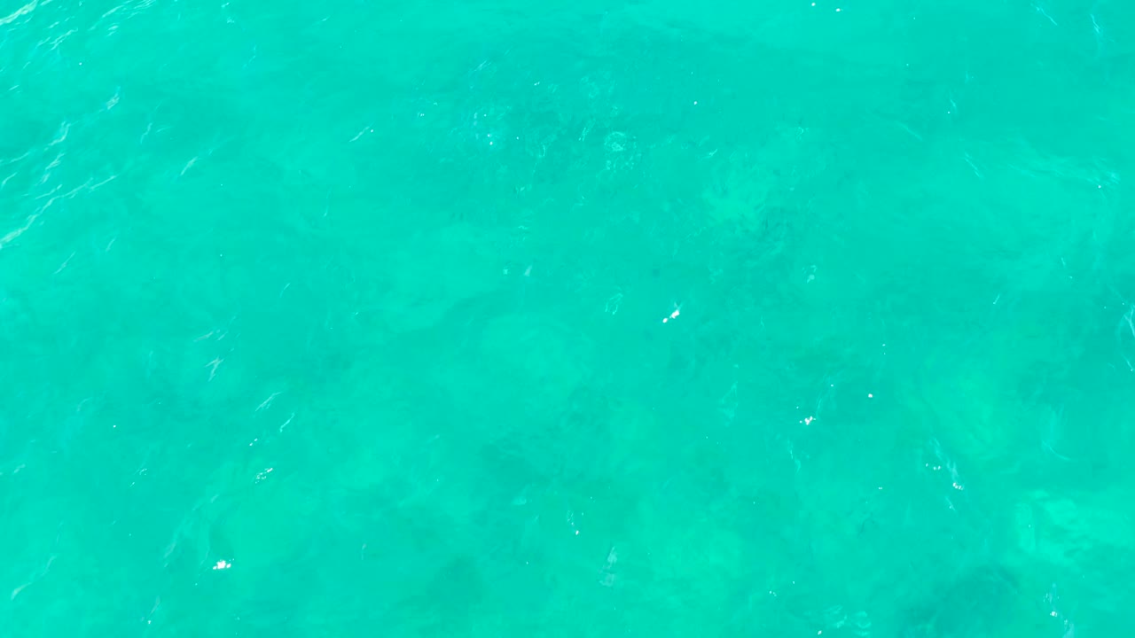 Clear turquoise sea in East Cape, Baja California Sur, Mexico, with soft ripples over darker seabed patches and no visible people.