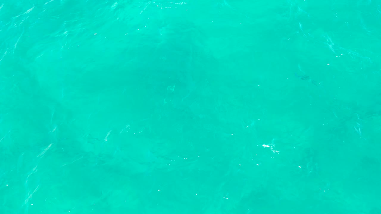Clear turquoise ocean water in East Cape, Baja California Sur, Mexico, with faint seabed patterns below the rippled surface and no visible people.