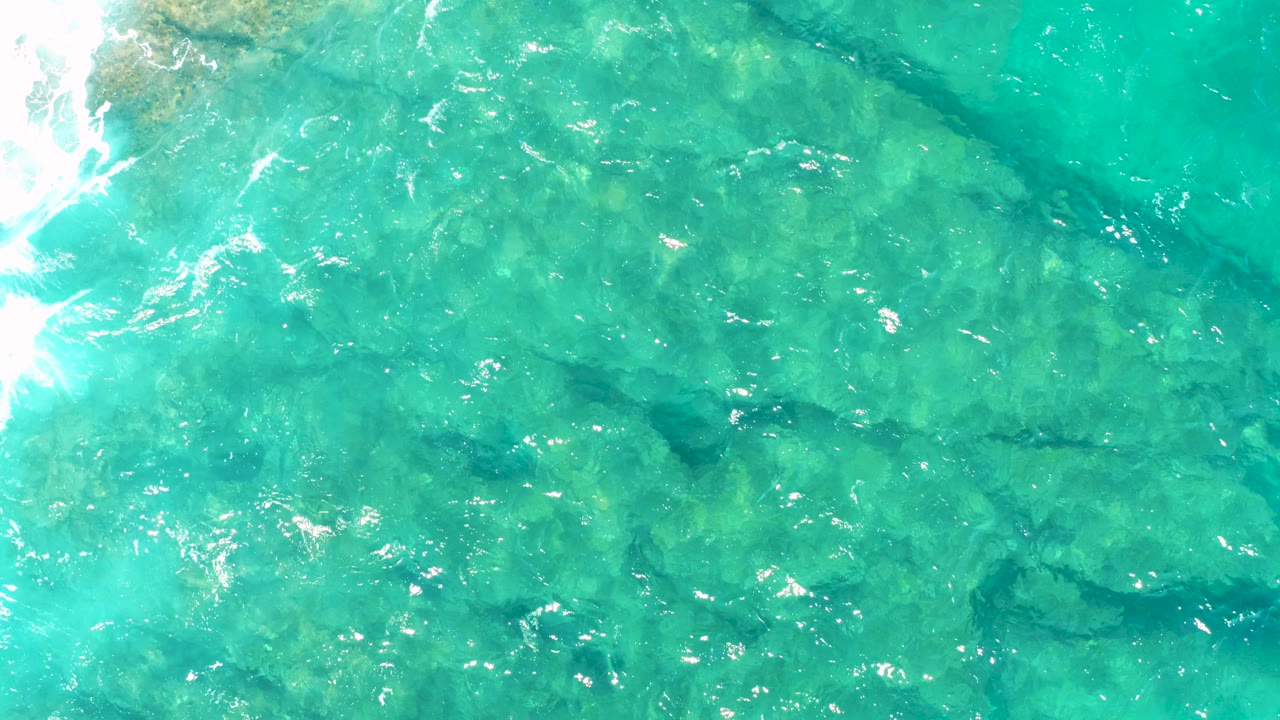 Turquoise shallow water over submerged rocks