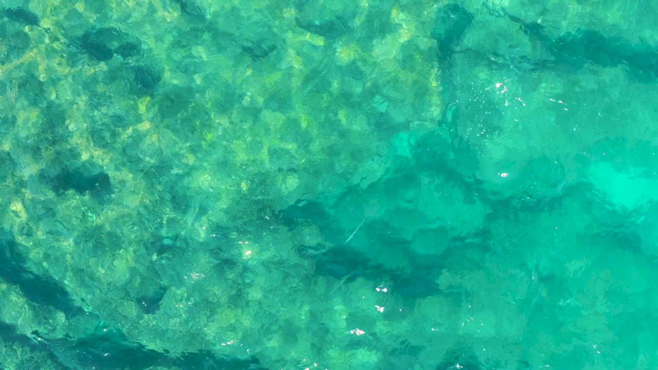 Shallow turquoise sea with underwater rocks and ripples