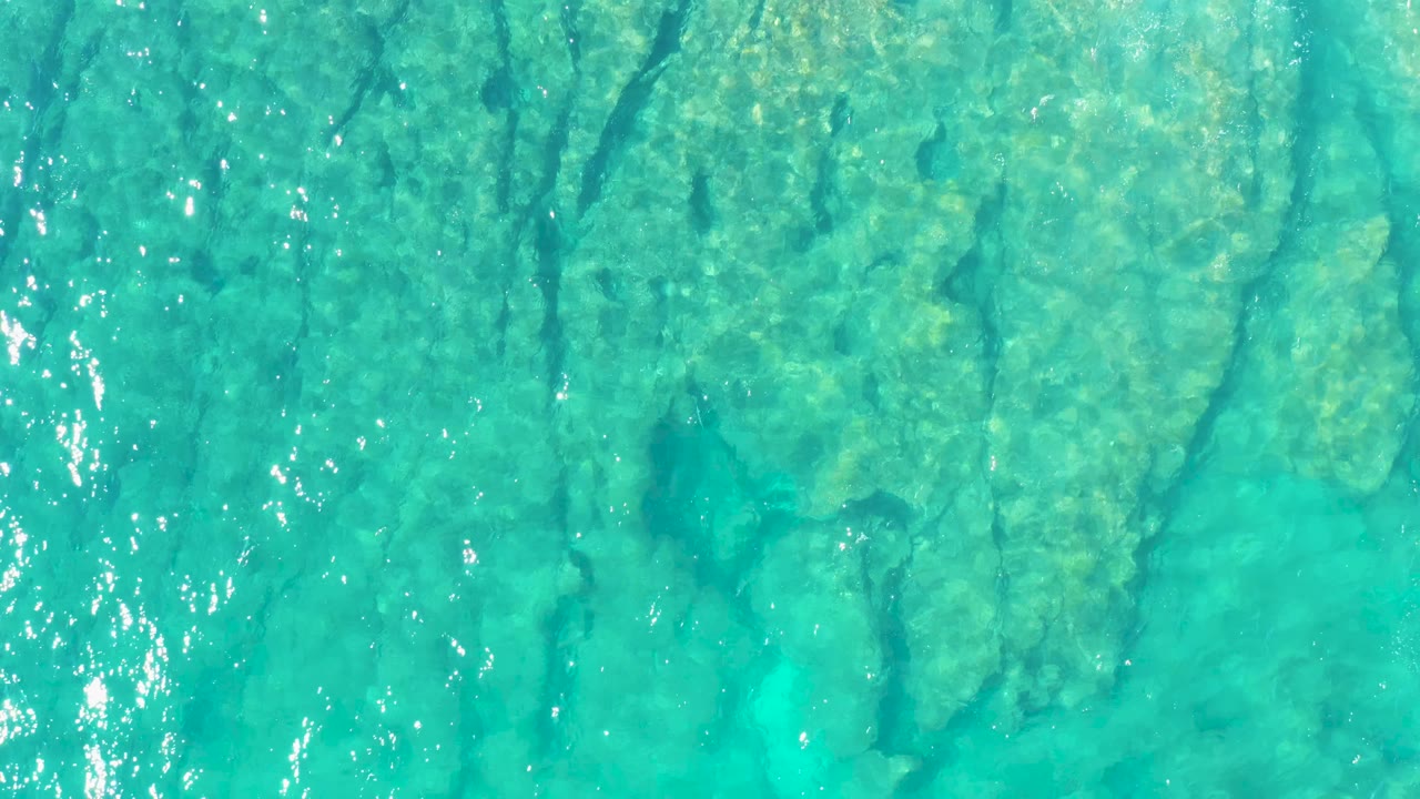 Blue-green ocean water reveals darker seabed lines below the rippled surface in East Cape, Baja California Sur, with no visible people.