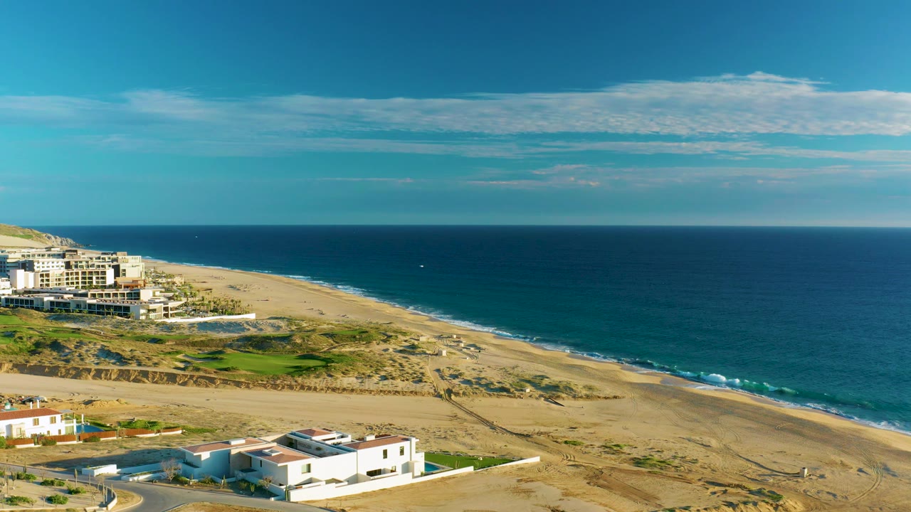 Aerial shoreline view with foreground houses and ocean beyond.