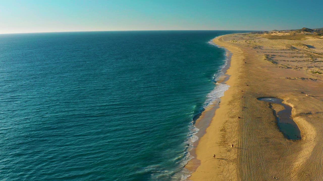 Aerial shoreline with teal water and empty sand