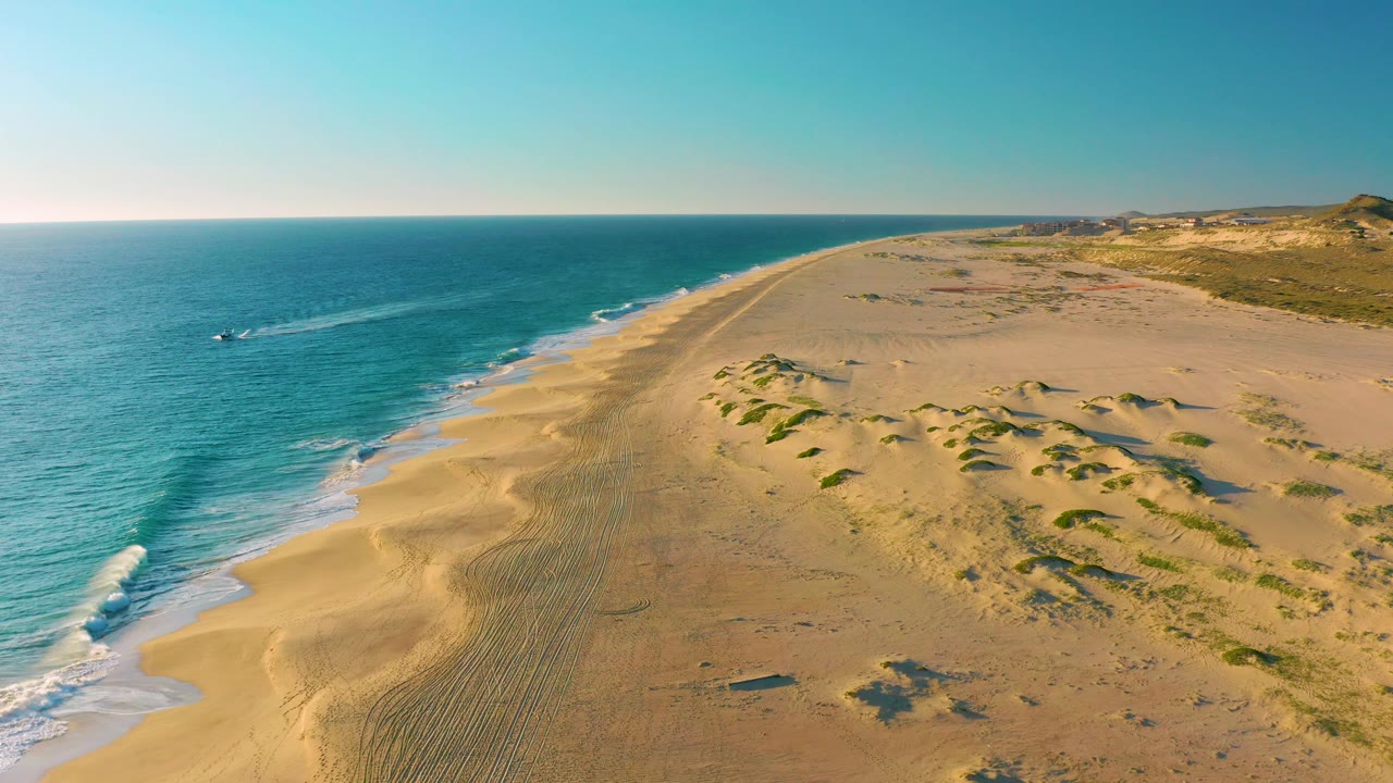 Oblique aerial view of beach dunes and ocean with boat wake