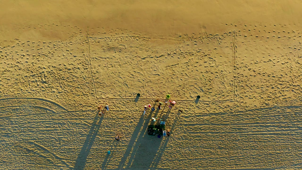 Aerial beach maintenance group beside tracks in sand.