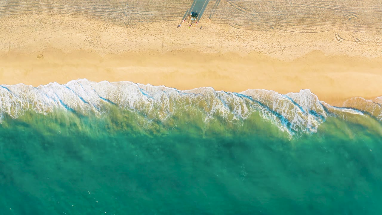 Overhead sand, surf, and small structure shadows
