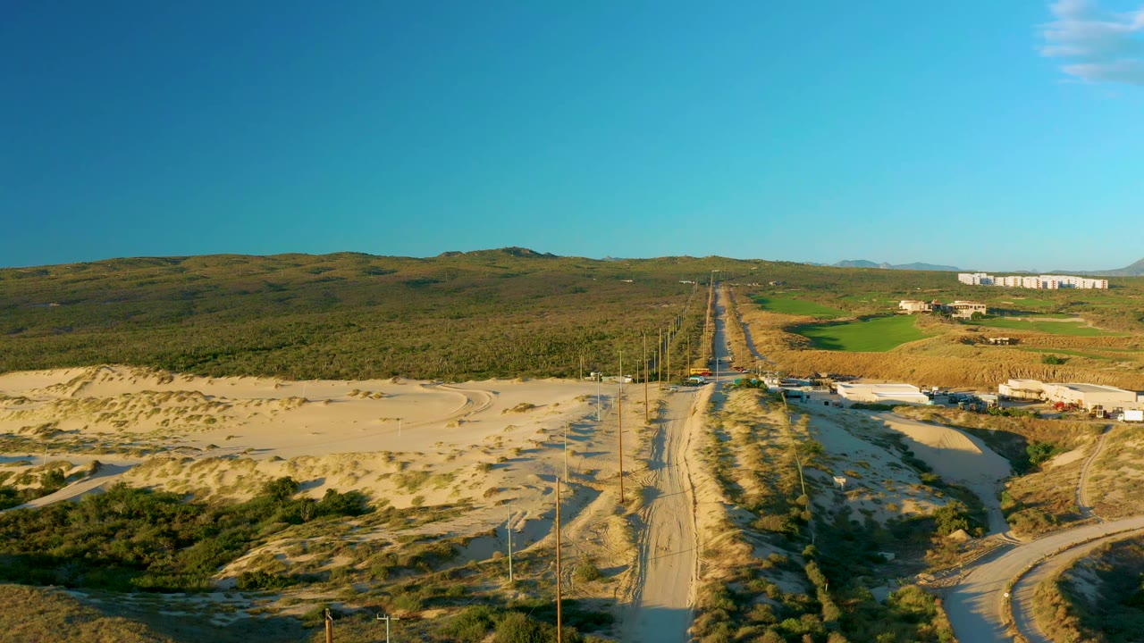 Sandy road and utility poles leading through sparse scrubland.