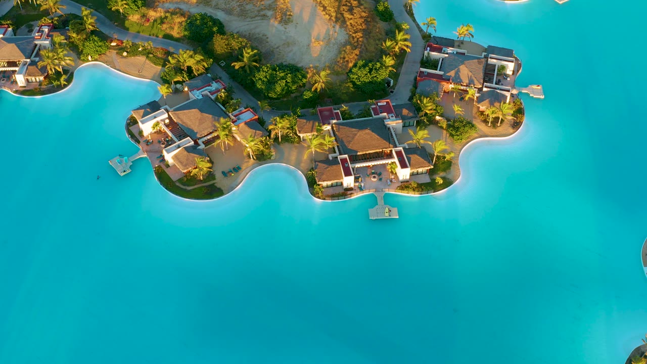 Lagoon-side bungalows with palms and sandy curved shore.