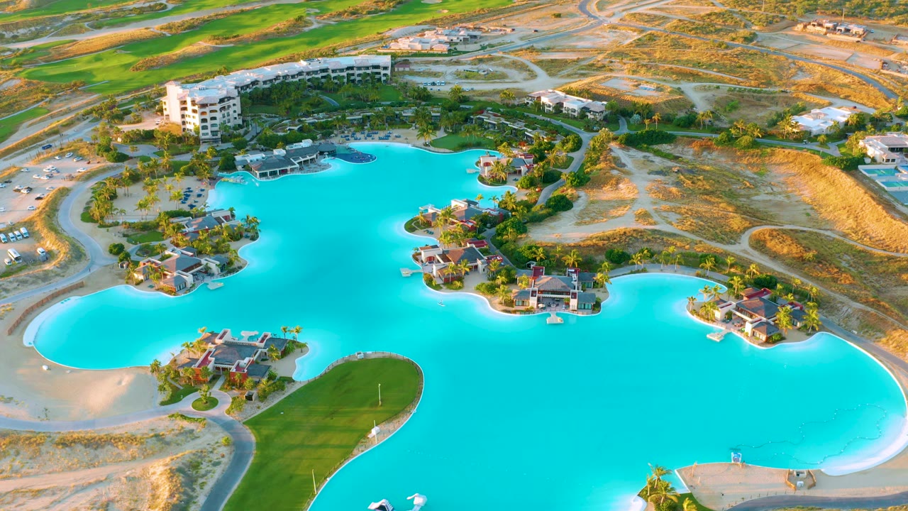 Artificial lake with residential islands, white building, and sandy banks from above.