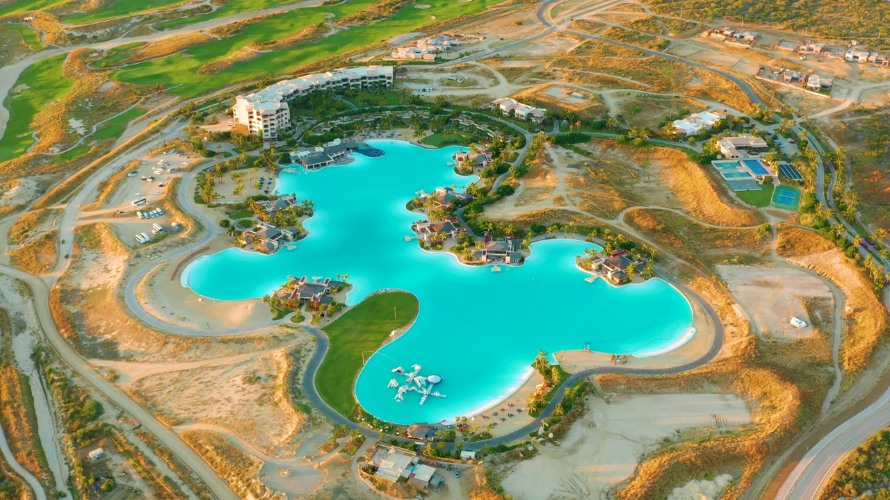 Aerial frame of the lake with islands, roads, grass, and surrounding construction land.