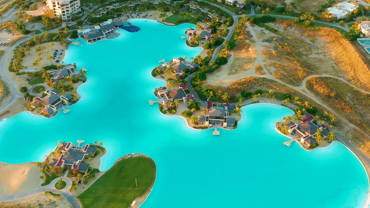 Aerial frame with blue lake, houses on islands, and a green shoreline area.