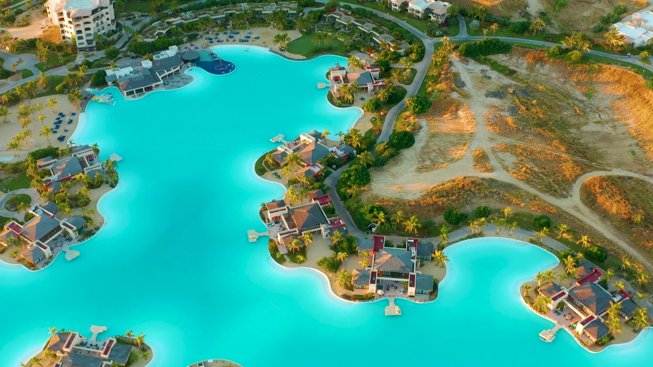 Third frame shows the Diamante Cabo San Lucas lagoon from above with turquoise water wrapping around villa clusters, dry sandy land, roads, and palms, with no visible people.