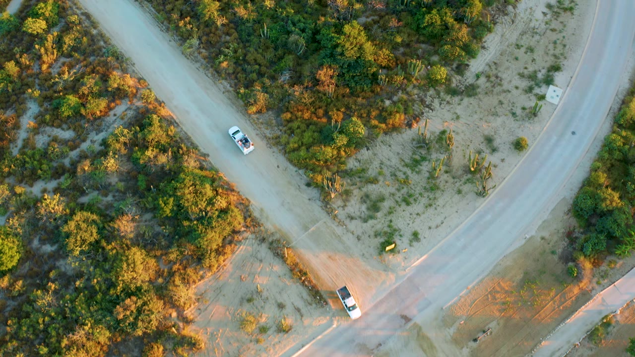 Aerial frame of a car on a diagonal rural road near a junction.