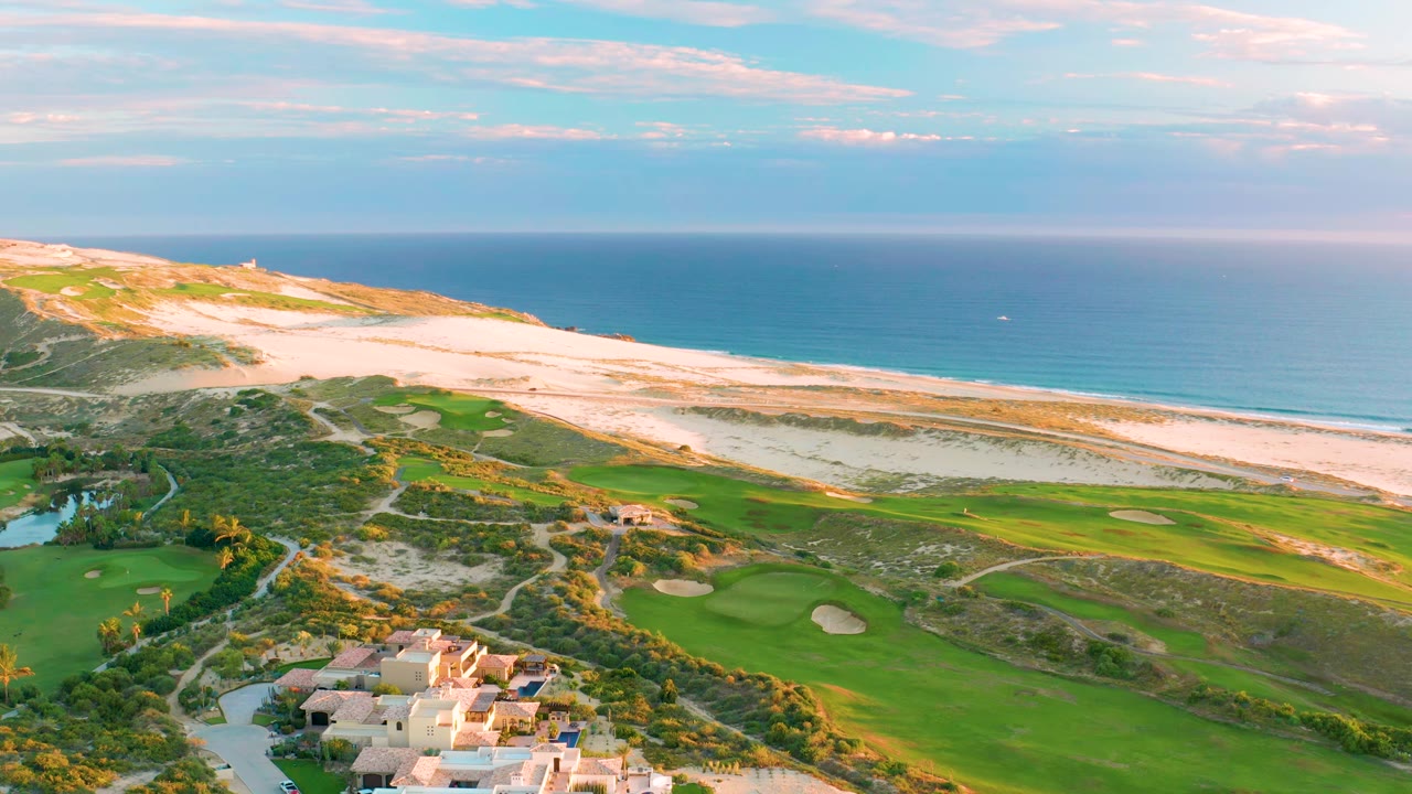 Coastal golf course below sand dunes and blue ocean